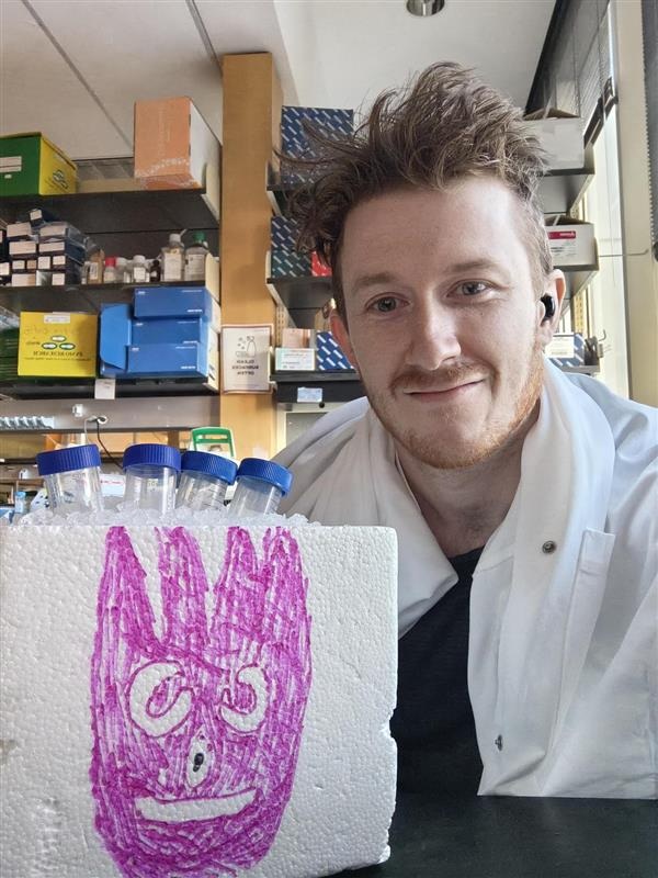A Choi Lab member holding a decorated foam cooler in the laboratory.