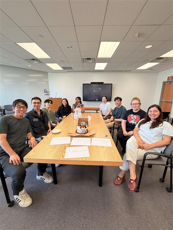 Choi Lab members seated around a table with a birthday cake.